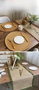 Detail of jute table runner featuring colorful pom-pom fringe and woven round placemat