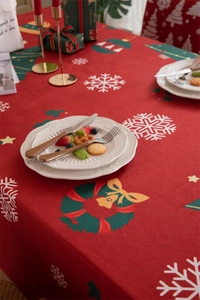 Festive red Christmas tablecloth detail with white snowflakes and green wreaths decoration