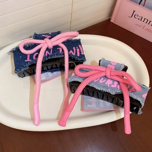 Detail of denim bow hair claw clips with pink graffiti text on a white ceramic plate