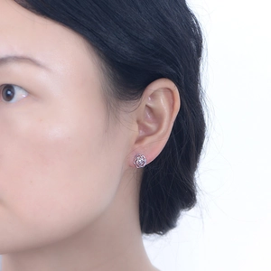 Detailed close-up of delicate silver hollow rose stud earrings worn on a female ear
