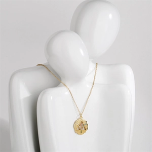 Detail of gold evil eye necklace with blue zircon on a white ceramic bust