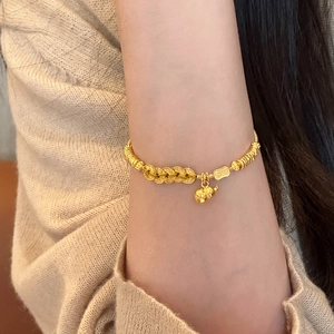 Golden Chinese gourd charm bracelet with lucky coin beads on a soft knit background