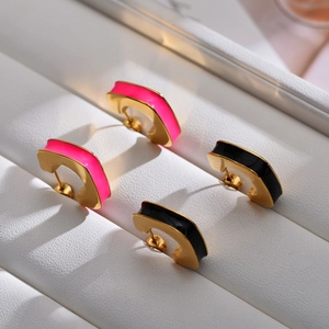 Macro shot of gold geometric C-shaped earrings with pink and black enamel finish