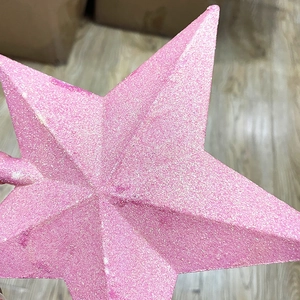 Close-up of pink glitter star topper showing textured shimmering surface for Christmas tree