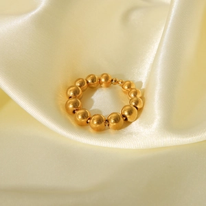 Macro shot of 18K gold plated stainless steel bead ring on soft beige silk fabric