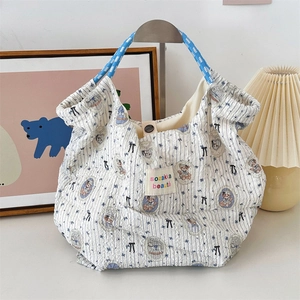 Detail of blue seersucker tote bag featuring vintage bear prints and woven rope handles