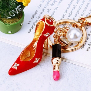 Detail of red high heel keychain with lipstick charm and white pearl on gold alloy ring