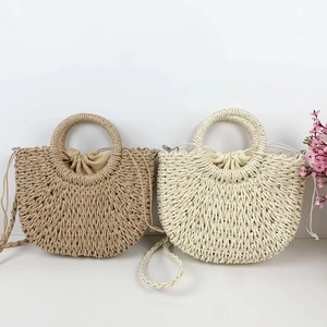 Detail of handmade straw handbags with round handles and drawstring lining in beige and white
