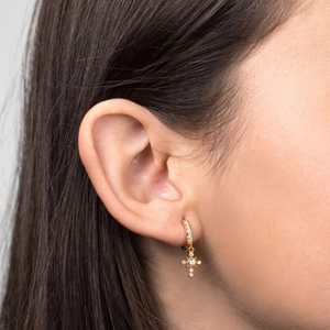 Luxurious gold hoop earrings with sparkling cross pendants worn on an earlobe