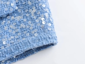 Macro shot of light blue tweed texture with sparkling sequins on stylish short jacket