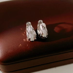 Detailed view of silver multifaceted faceted earrings on dark brown leather texture