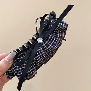 Close-up of blue plaid fabric hair claw clip with black ribbon bow and crystal detail