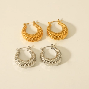 Macro detail of gold and silver croissant hoop earrings with glossy twisted texture