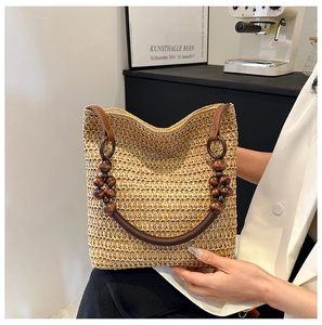 Detail of hand-woven rainbow straw tote bag featuring brown wooden beads and leather strap