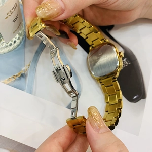 Detail of the golden metal watch featuring a butterfly clasp and solid steel strap