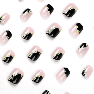 Faux ongles courts carrés avec motif diagonal rose et noir et décorations de marguerites