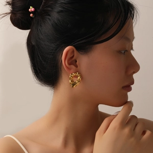 Detail of model wearing gold irregular geometric earrings with hammered texture finish