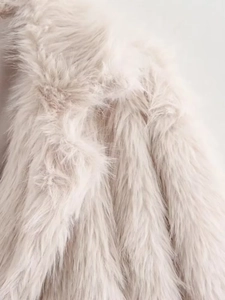 Macro shot of fluffy light beige faux fur texture showing soft and dense fibers