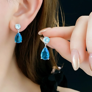 Close-up of a blue teardrop stone earring on a model, elegant silver jewelry set