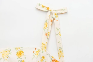 Detaillierte Makroansicht des cremefarbenen Stoffes mit gelbem Blumendruck und Bindeband
