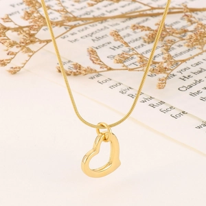 Minimalist gold hollow heart pendant on thin snake chain over artistic paper and dried flowers
