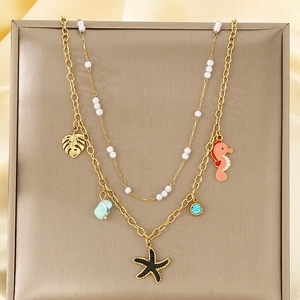 Vue détaillée du collier double couche doré avec breloques étoile de mer, hippocampe et perle
