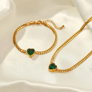 Nahaufnahme eines goldfarbenen Schmucksets mit herzförmigen grünen Edelsteinen.