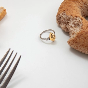 Détail macro du charm croissant doré sur une bague en acier au design de fourchette