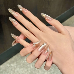 Long almond cat-eye press-on nails with champagne ribbons and pearl accents