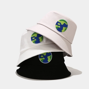 Close-up of three cotton bucket hats with colorful globe embroidery in neutral colors