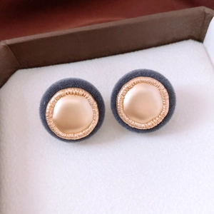 Macro shot of retro grey plush and gold metal button earrings in jewelry box