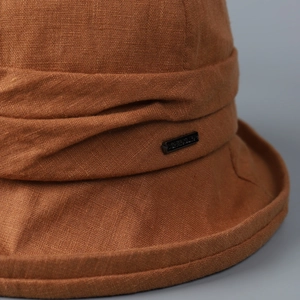Macro detail of high-quality linen bucket hat fabric with pleated band and metal logo