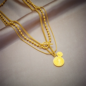 Collana multistrato in acciaio al titanio dorato con ciondoli a moneta e chiusura OT