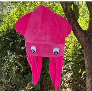 Gedetailleerd beeld van de roze pluche octopushoed met cartoonogen hangend aan een tak