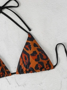 Detail of leopard print triangle bikini top with orange-red pattern and black ties