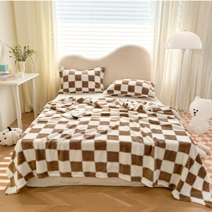 Detail of plush brown and white checkered blanket set with matching pillowcases on bed