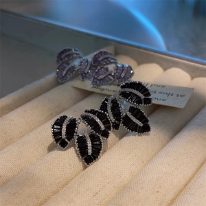Detailed close-up of leaf-shaped earrings with black and purple stones in a jewelry box