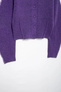 Dettaglio del cardigan in maglia viola che mostra il tessuto, l'orlo e quattro bottoni classici