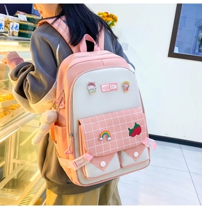 Pink and white student backpack with cute badges and fashion patches shown in a lifestyle setting