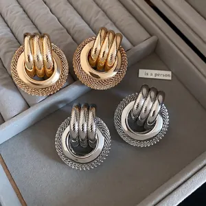 Boucles d'oreilles rondes en métal torsadé doré et argenté sur plateau velours