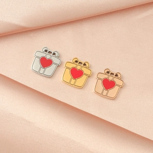 Drei spiegelpolierte Geschenkbox-Anhänger in Silber, Gold und Roségold mit roten Herzen