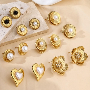 Detailed shot of vintage gold pearl earrings and black gemstones on silk and stone background