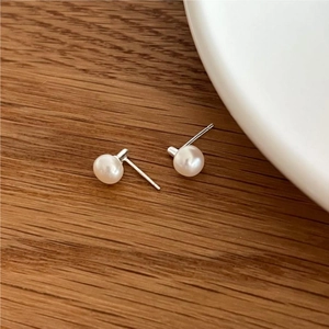 Minimalist S925 sterling silver freshwater pearl stud earrings on a dark wood background