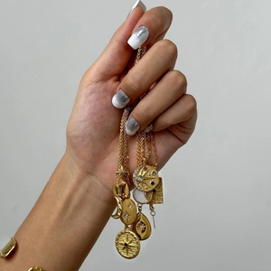 Multiple gold stainless steel necklaces with star and moon pendants held in hand