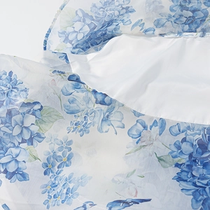 Detail of blue floral chiffon fabric with white lining on a one-shoulder dress
