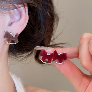 Close-up of velvet horse earrings with silver base and rhinestone details