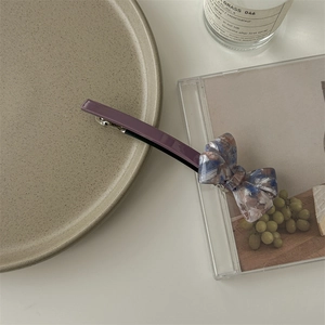 Detail view of purple acetate hair clip with marble pattern bow on a ceramic plate