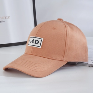 Detailed close-up of light brown baseball cap with embroidered AD patch and cotton texture