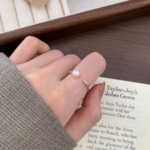 Minimalist silver open ring with round white pearl featured on hand in elegant setting