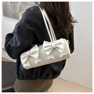 Chic white bow cylinder bag worn by a model in a trendy street style outfit
